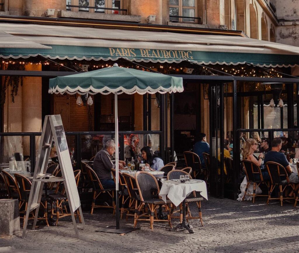 a group of people sitting at tables outside a restaurant
