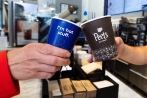 two hands holding cups with text on them