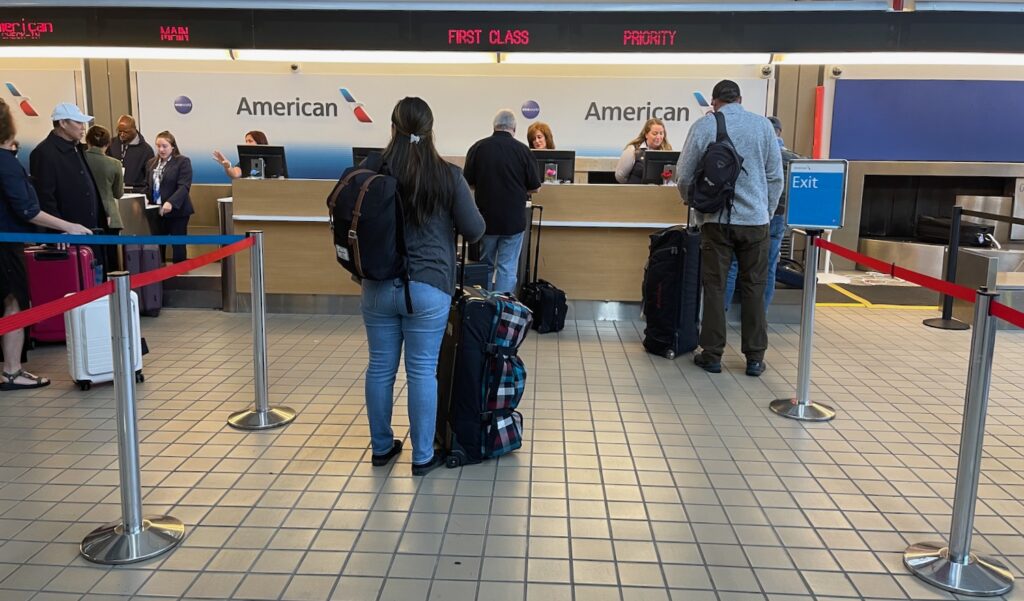 people standing in front of a desk with luggage