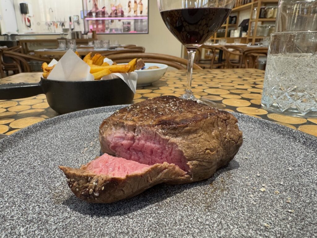 a steak on a plate with a glass of wine