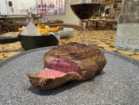 a steak on a plate with a glass of wine