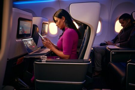 a woman sitting in an airplane with a laptop and a phone