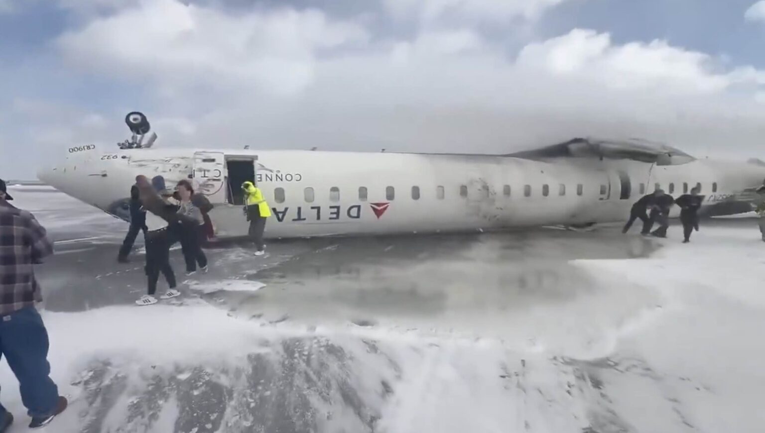 a group of people standing next to a plane that has been crashed