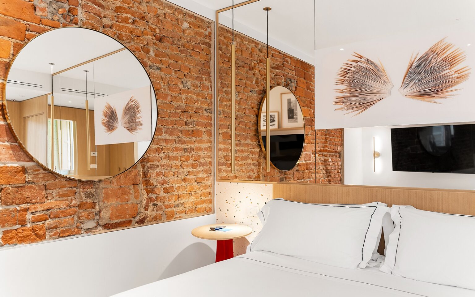 Milu opens in Milano round mirror on exposed brick wall in hotel guestroom