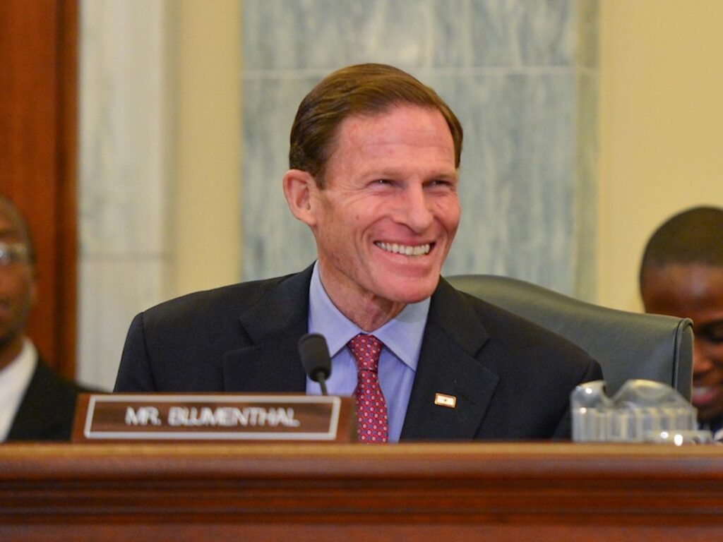a man in a suit smiling at a podium