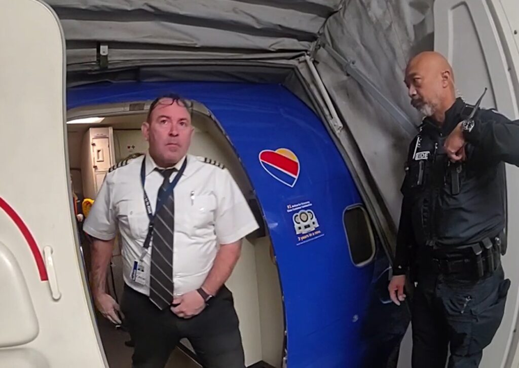 a man standing in a blue tent next to a man in a white shirt