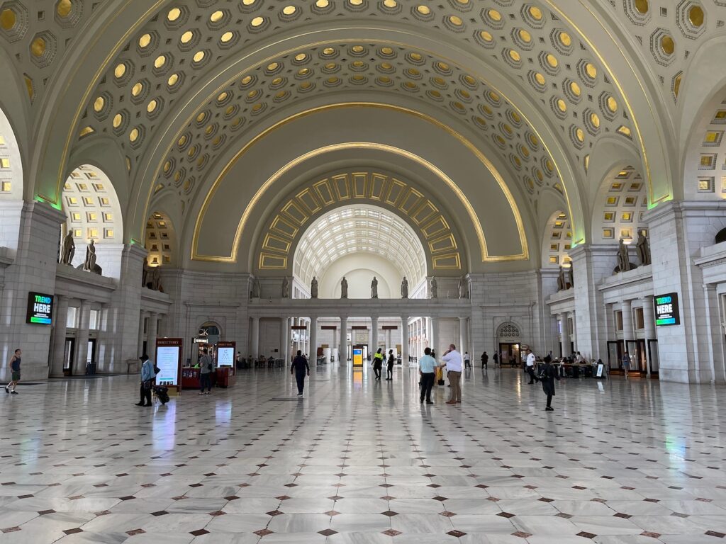 a large white building with many people walking around with Union Station in the background