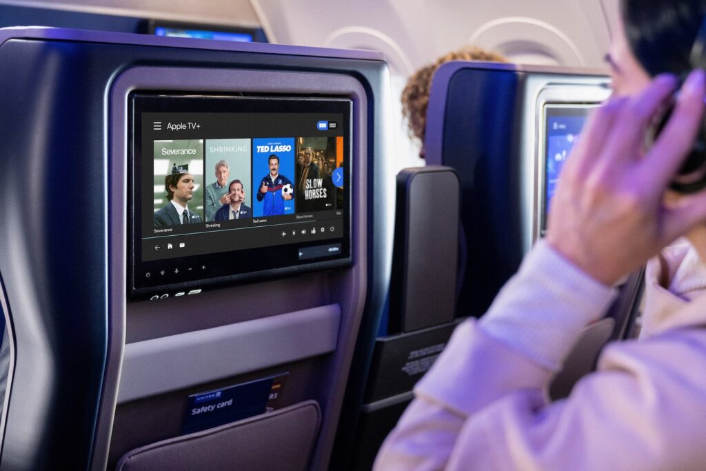 a man sitting in an airplane with a screen on
