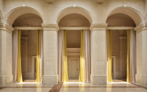3 arches in cream stone framed with yellow floor to ceiling curtains in Vista Ostuni - a five-star luxury hotel and part of the Vista brand