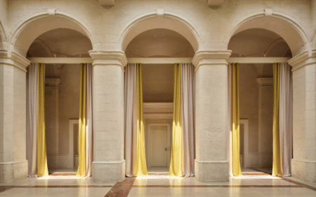 3 arches in cream stone framed with yellow floor to ceiling curtains in Vista Ostuni - a five-star luxury hotel and part of the Vista brand
