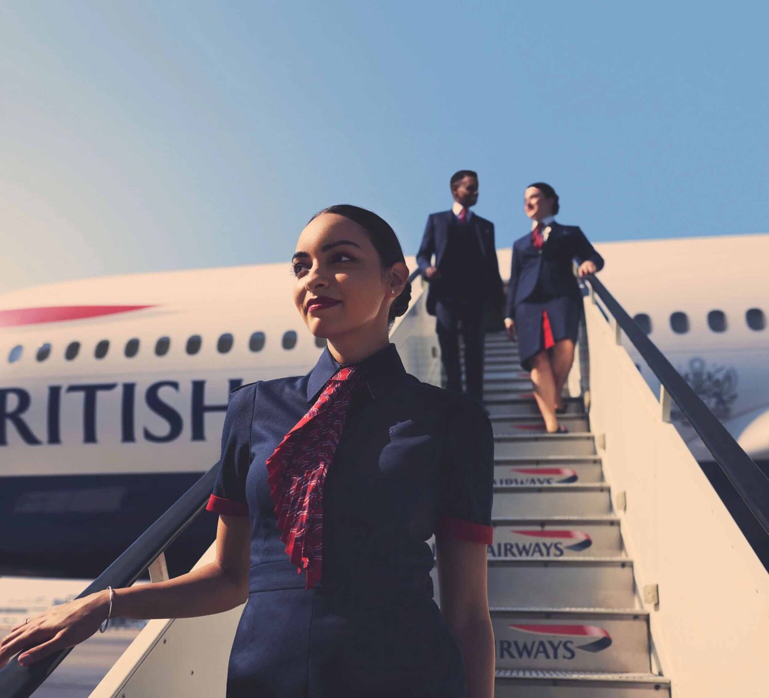 a woman in uniform standing on stairs of an airplane