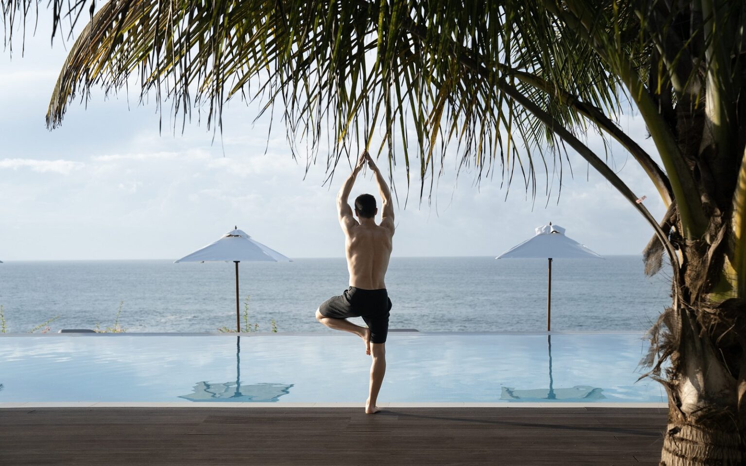 Uga Prāva opens in Tangalle, Sri Lanka man in yoga pose next to palm tree and pool at Uga Prāva Sri Lanka