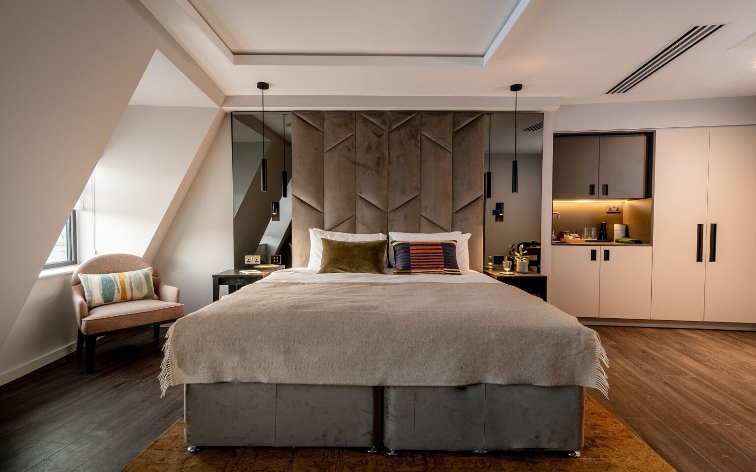 The Hobson Cambridge by Adina – a historic landmark reborn grey bed with white linen on wood floor in aparthotel suite Adina The Hobson
