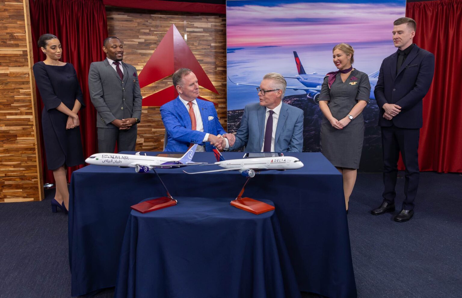 Delta Air Lines Signals Middle East Ambitions With Atlanta–Riyadh Flight a group of people standing around a table with a model airplane
