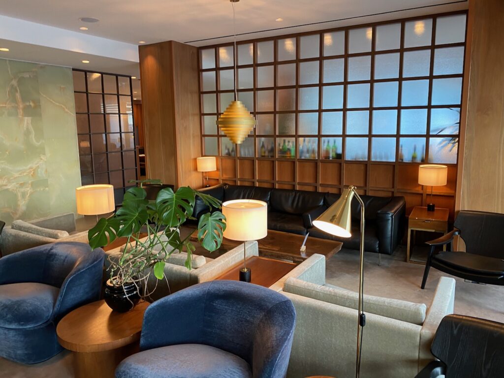 If I Had To Pick An Airport Terminal To Live In… Barista-made coffee with frothy top, accompanied by fresh strawberries in a bowl, set on a black marble table, reflecting the luxurious dining experience in the Qantas lounge at London Heathrow Terminal 3.