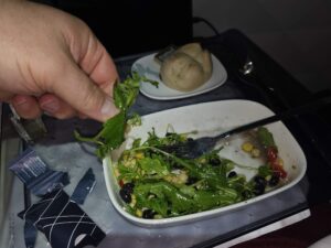a hand holding a fork over a salad