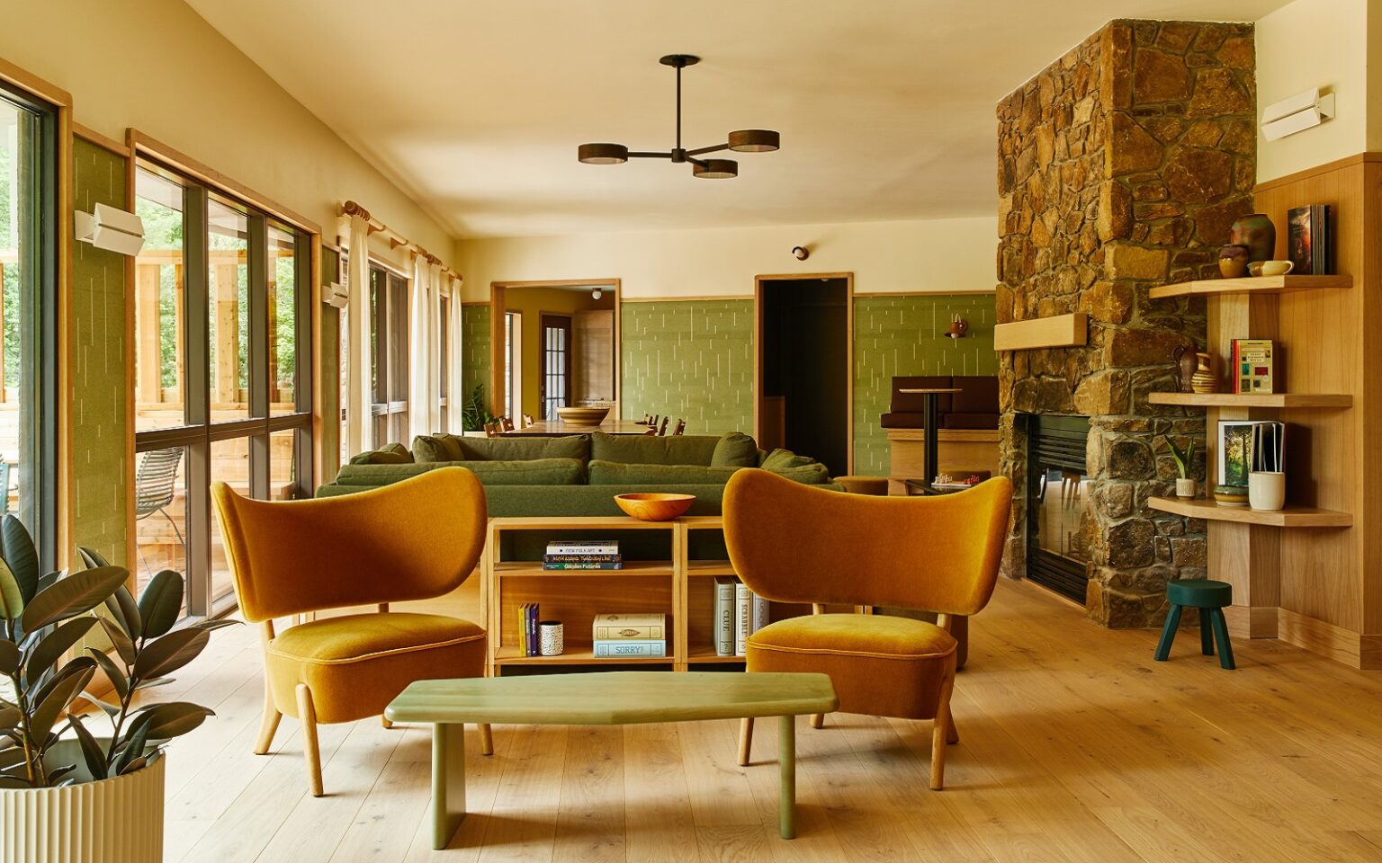 Trailborn Hotels & Resorts joins new Outdoor Collection by Marriott ochre chairs and olive green walls with stone fireplace in lounge of Trailborn Highlands hotel