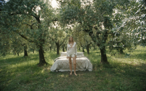 bed made up with Frette bed linen in the middle of olive grove with model in Frette bed wear