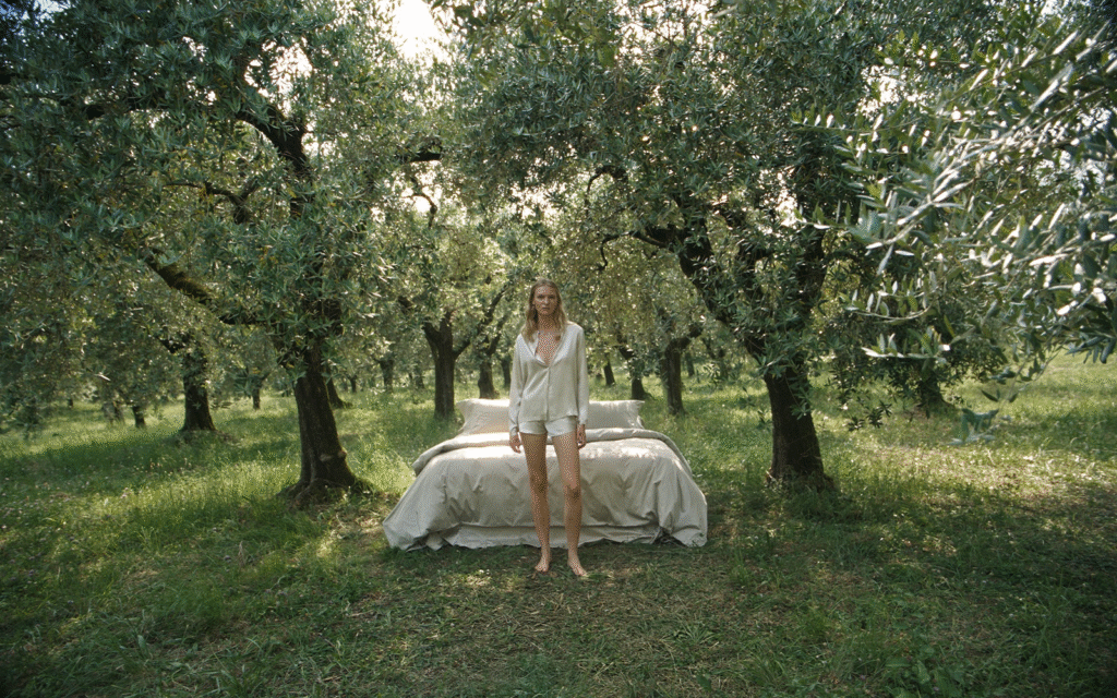 The Bed is a Place – a new chapter from Frette bed made up with Frette bed linen in the middle of olive grove with model in Frette bed wear