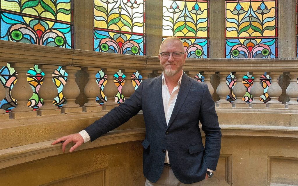 TFE Hotels, Europe appoints Ray Goertz as UK Regional GM portrait of Ray Goertz next to stained glass window on stairway of Hobson Cambridge by Adina