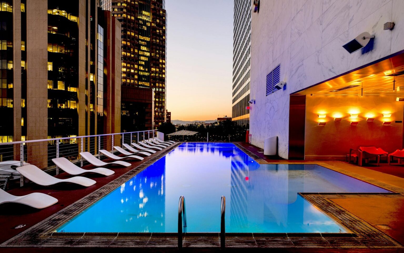 Storytelling – the new standard of hotel luxury hotel swimming pool with view through highrise buildings to sunset