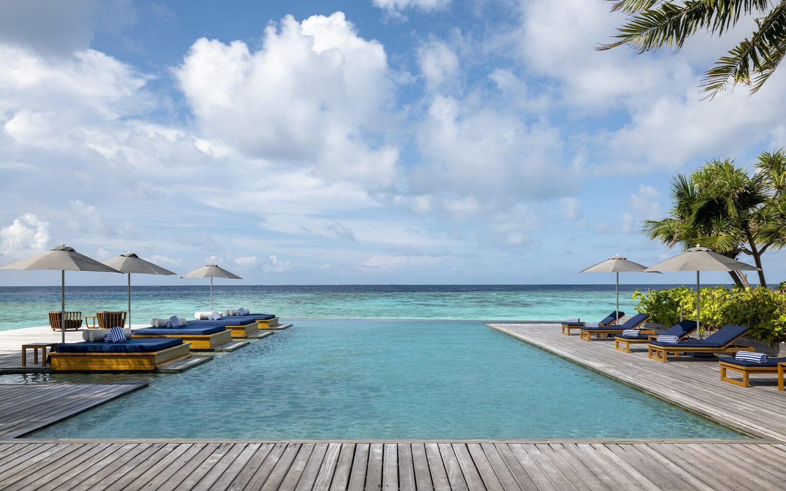 hotel infinity pool surrounded by wooden deck extending out to sea on island in the Maldives