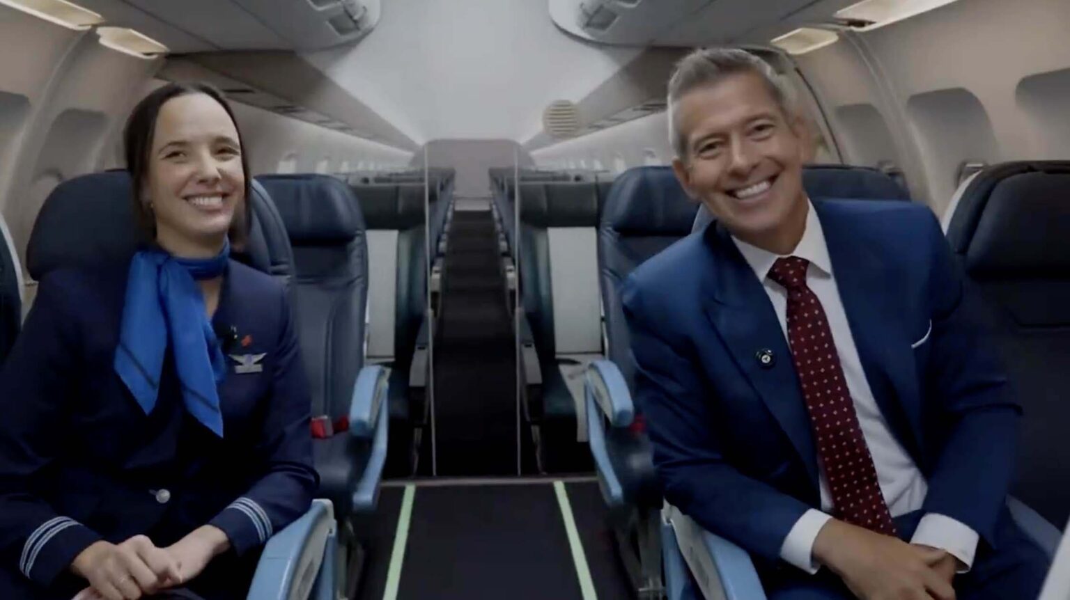 two men in suits sitting in an airplane