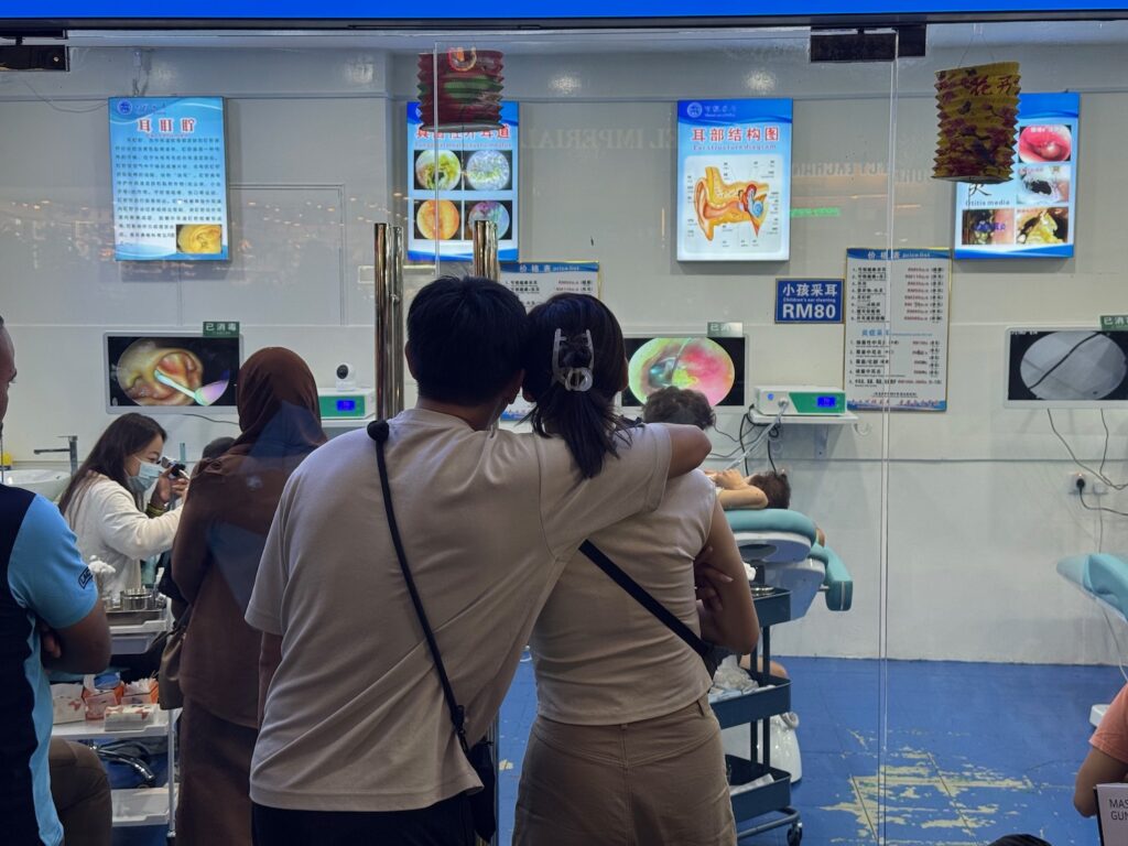 An Ear Picking Date Night In Kuala Lumpur? a man and woman standing in front of a window