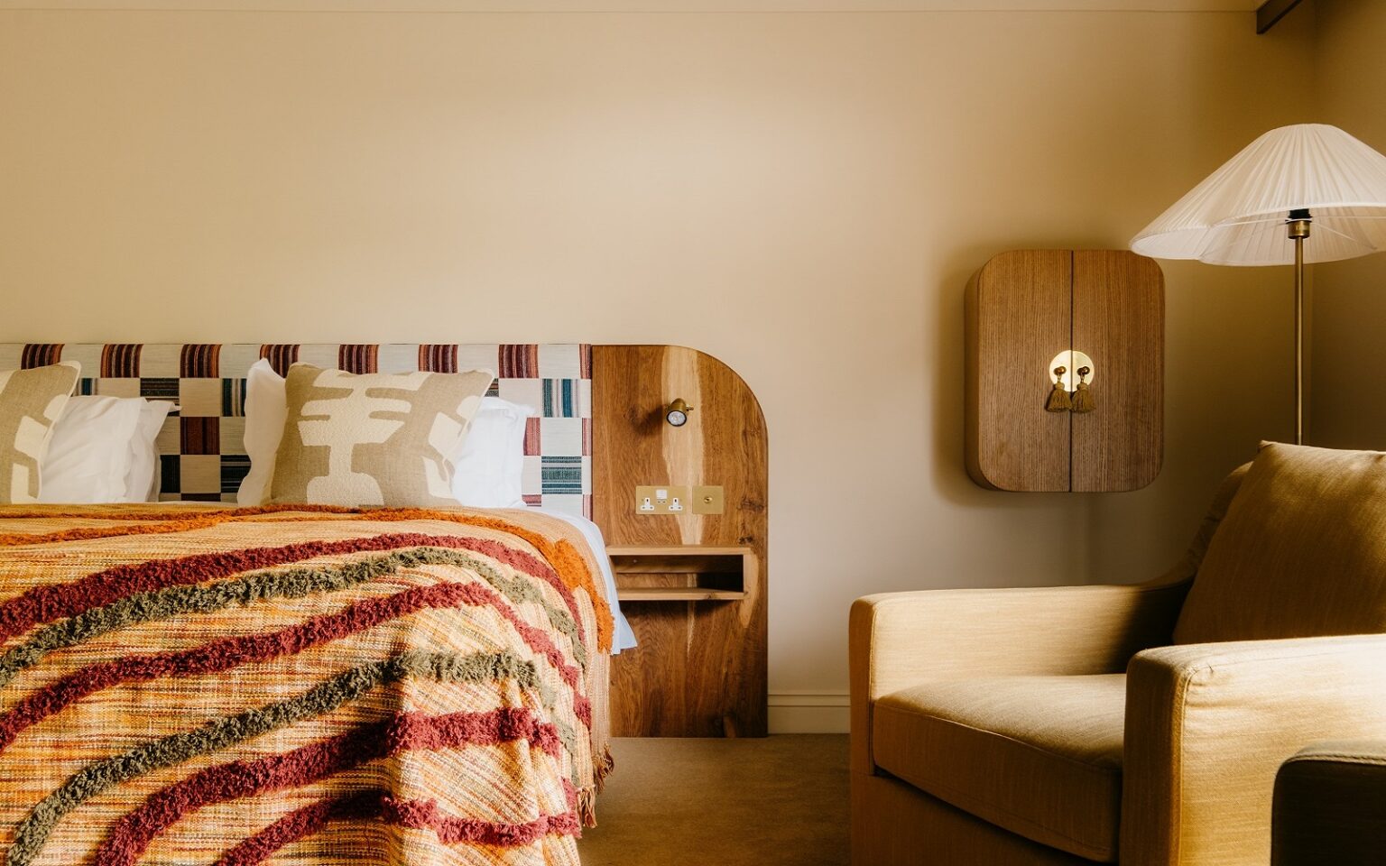 striped woven throw on bed with hand crafted cushions and wooden headboard
