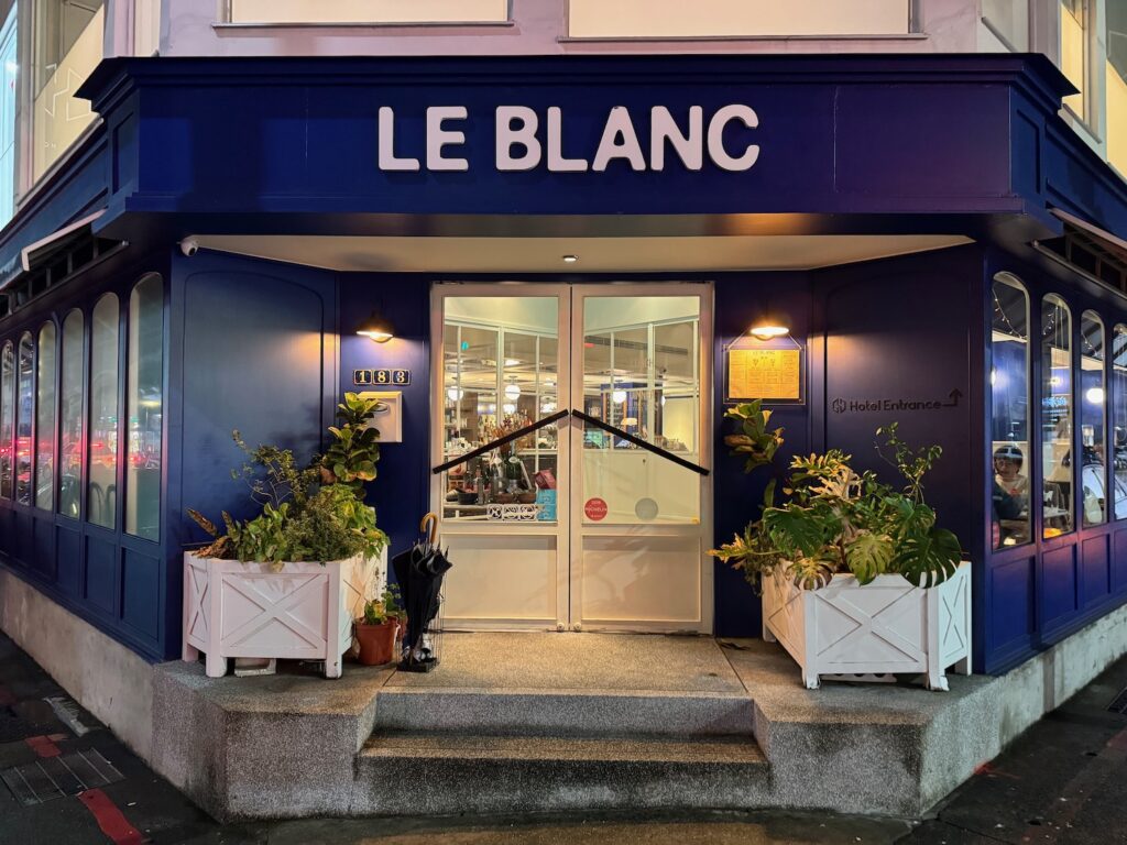 a store front with a sign and plants