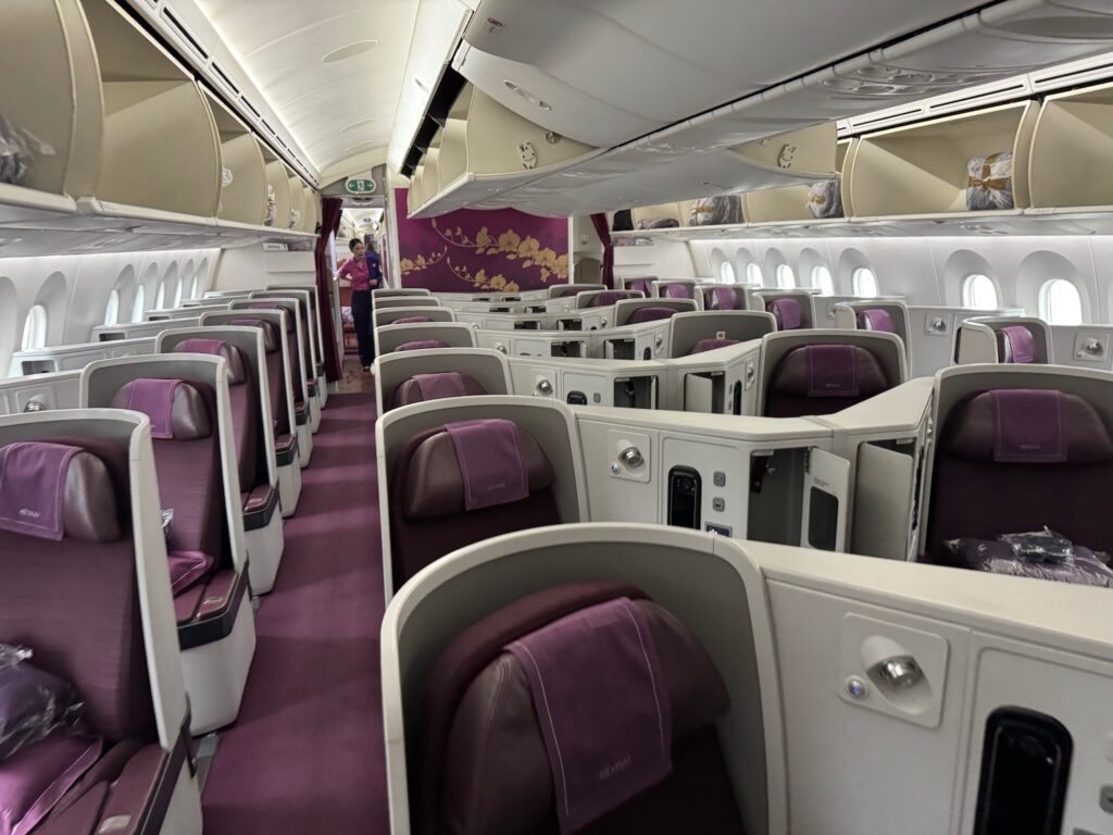 A 2-Hour Flight, A Lie-Flat Bed, Caviar, And A Real Blanket. Only In Asia. a inside of a plane with purple seats
