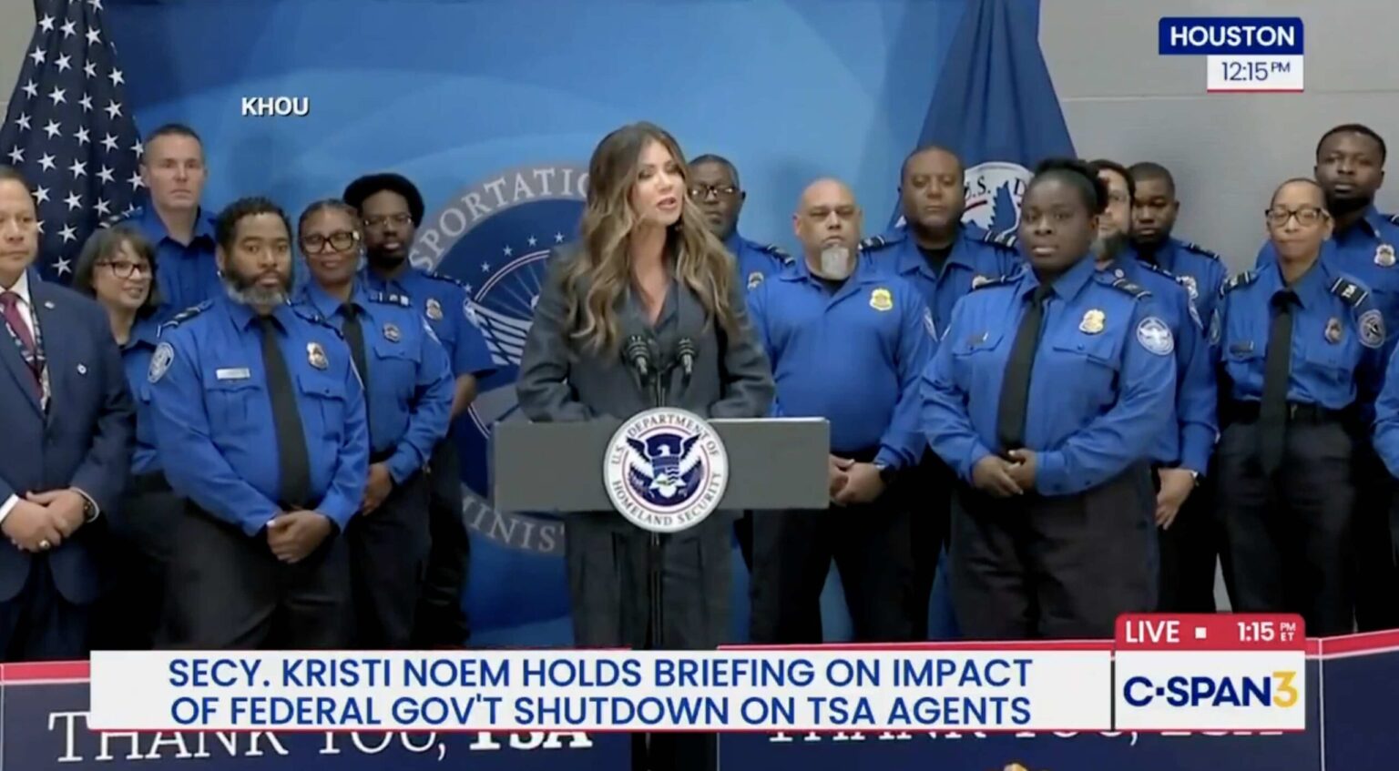Trump Gives “Patriot” TSA Agents $10,000 Bonuses For “Exemplary Service” During Shutdown a woman standing at a podium with a group of people behind her