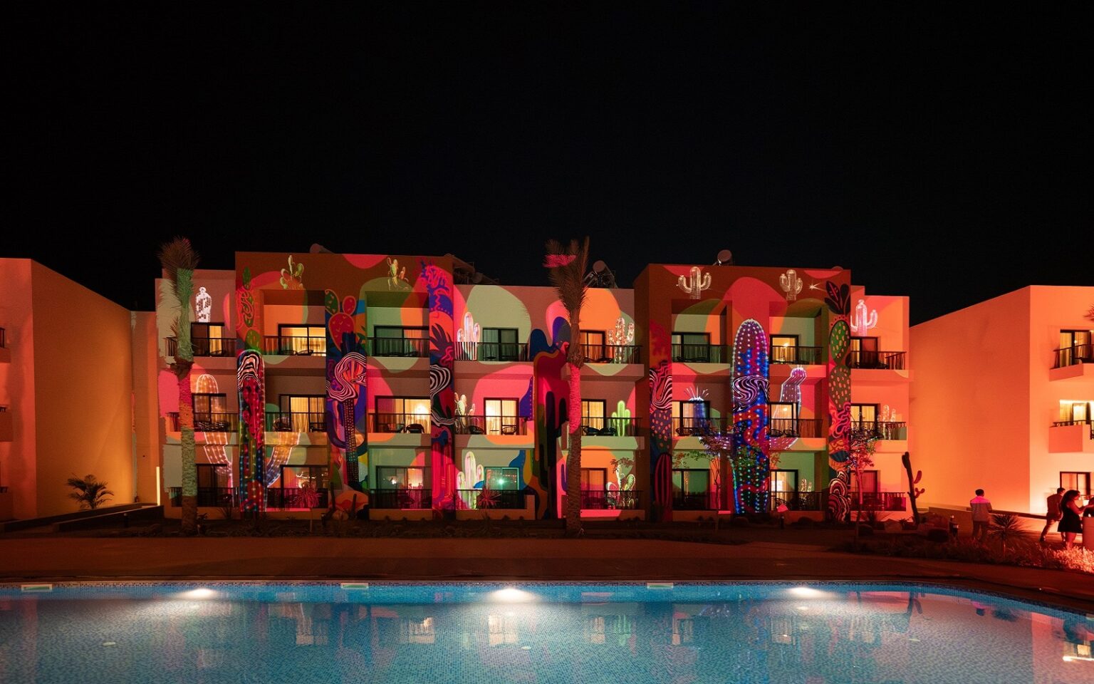 night lights across pool and cactus mural at Kaktus Hotel & Co-Working Hub, SomaBay