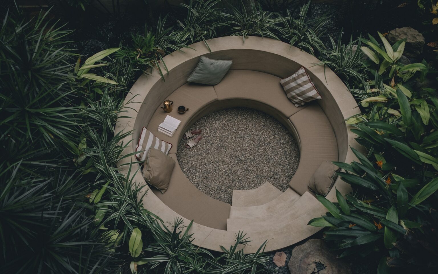 circular outdoor seating pit surrounded by tropical plants at Mantra Hotel in Mexico