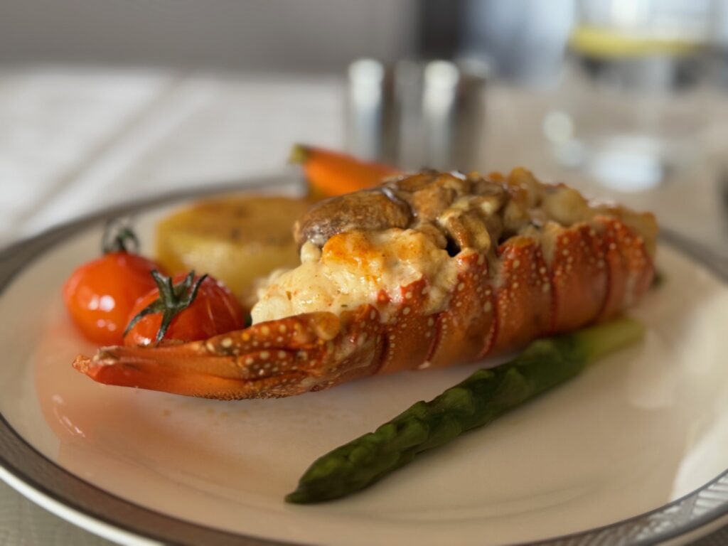 My Top 10 Airline Meals Of 2025 a lobster tail with vegetables on a plate