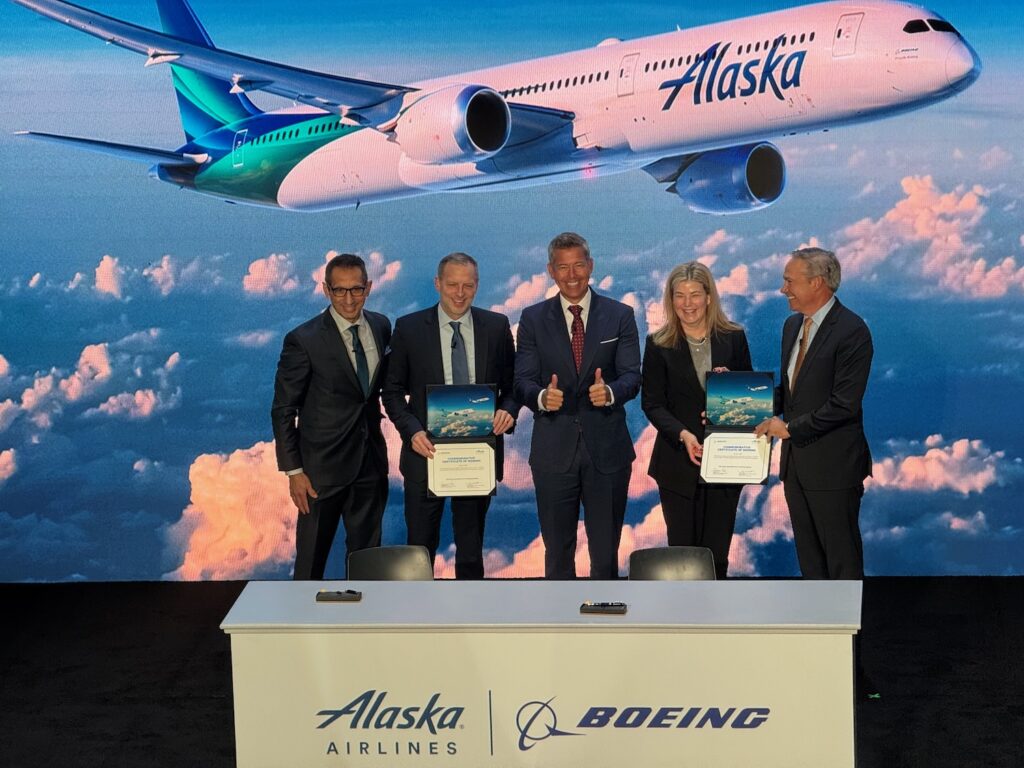 a group of people standing in front of a wall with an airplane behind them