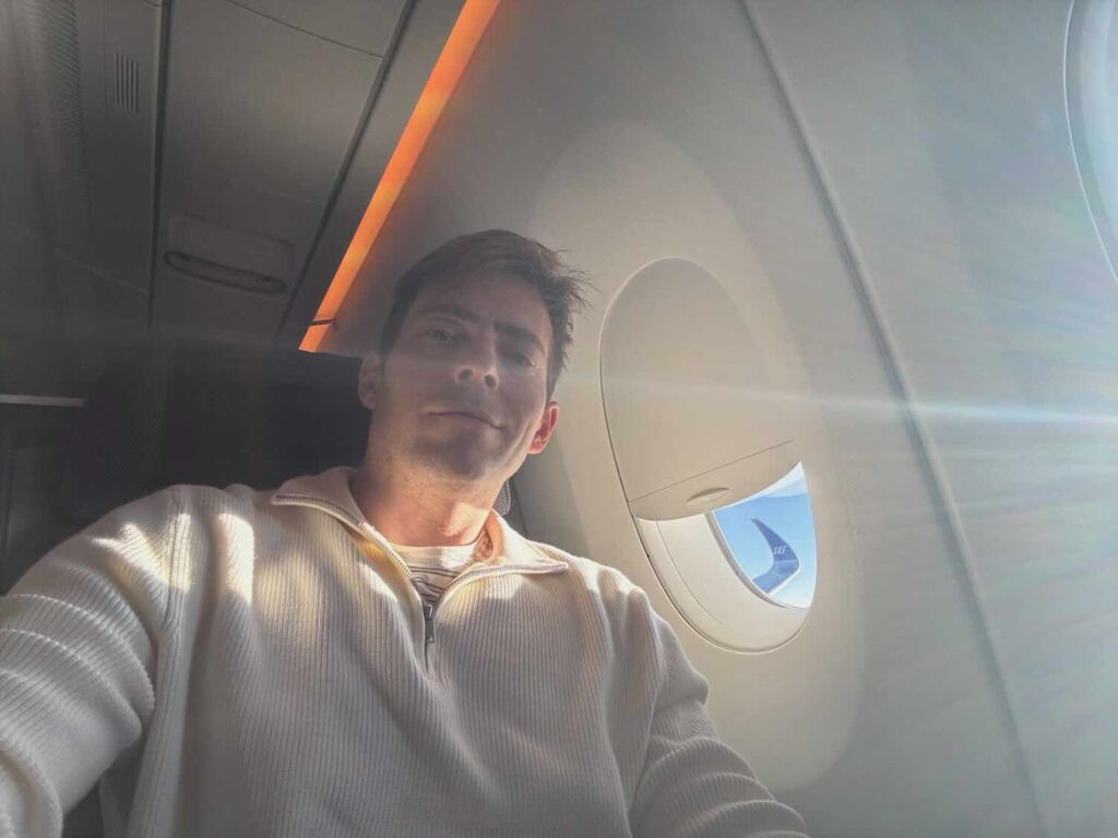 My 2026 Elite Status Strategy: Embracing Free Agency Across Airlines And Hotels a man taking a selfie in an airplane