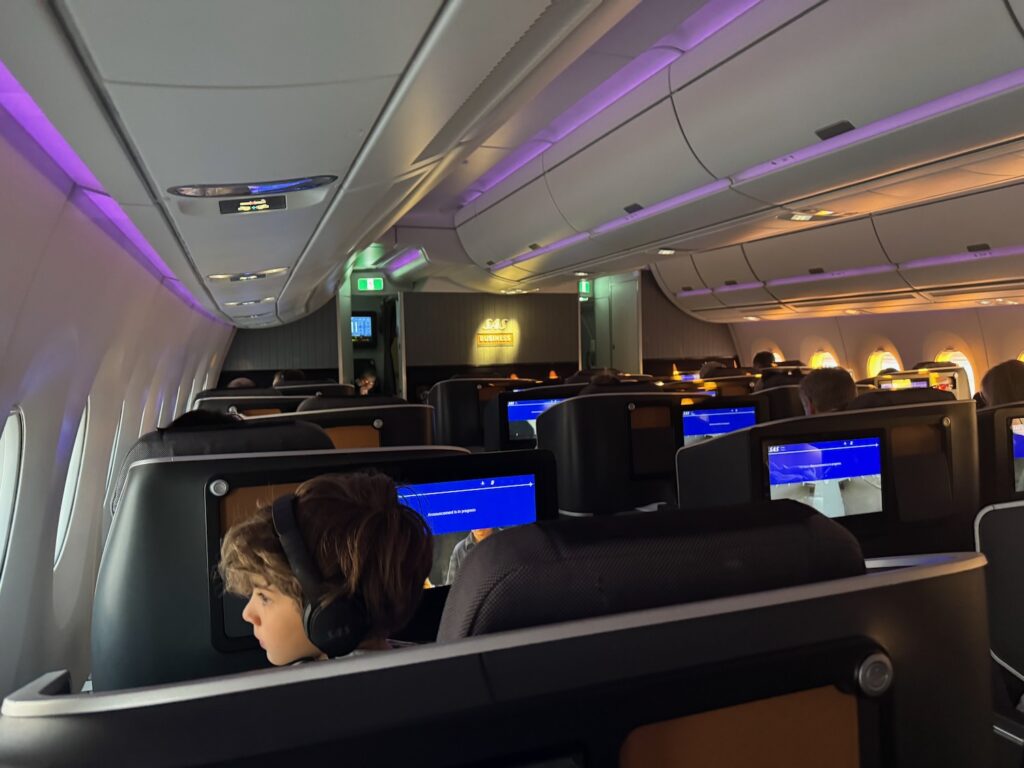 a boy sitting in an airplane with a computer