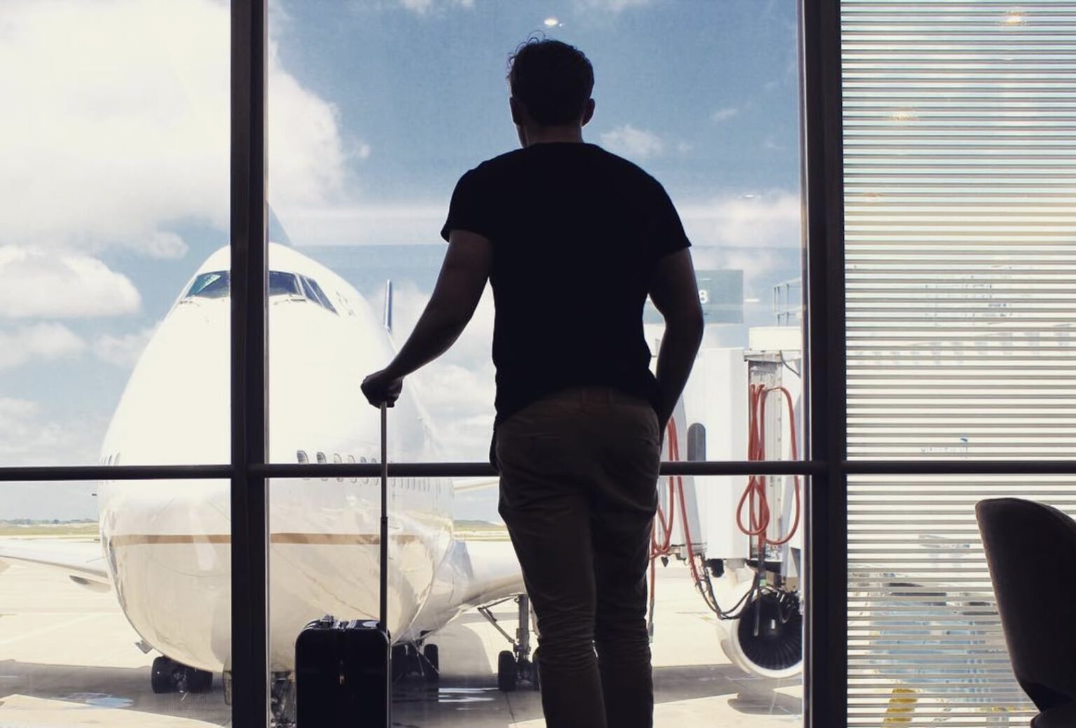 a man standing in front of a window with a suitcase