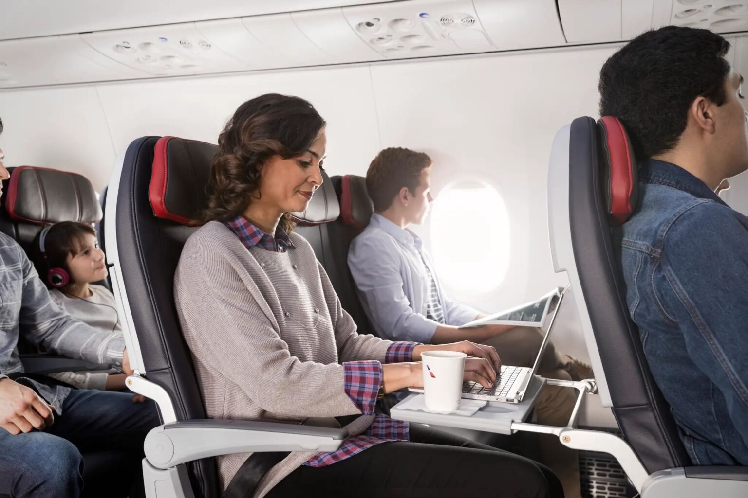 a woman sitting in an airplane with a laptop