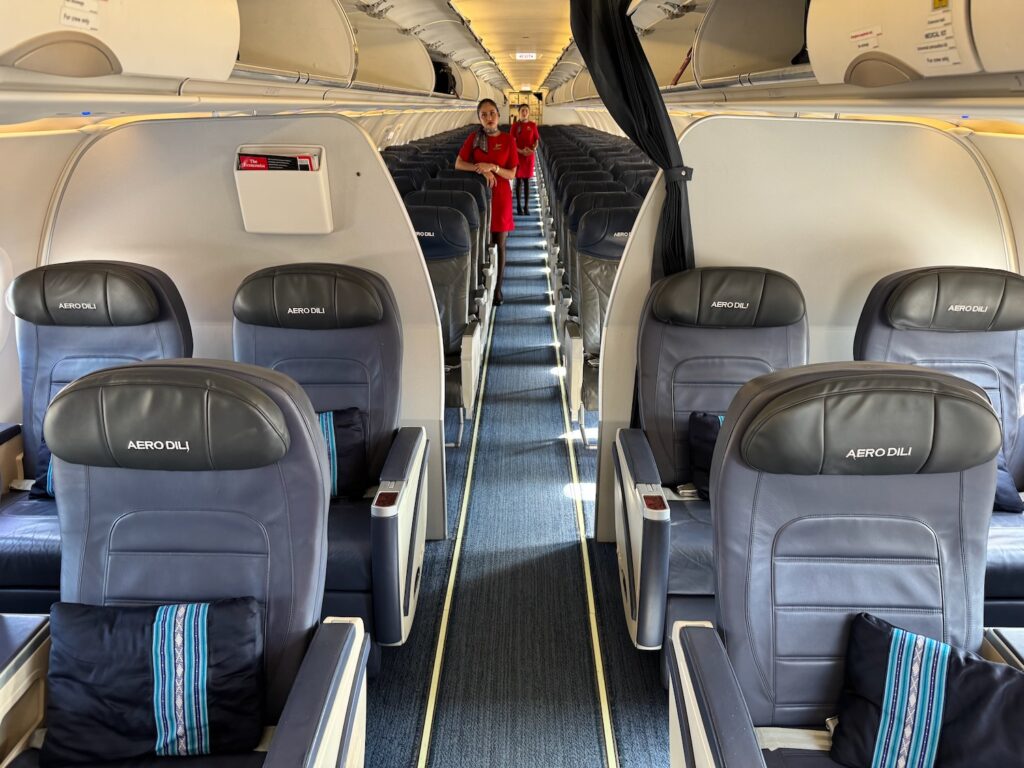 Review: Aero Dili A320 Business Class a woman standing in the middle of an airplane