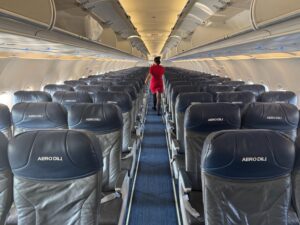 Review: Aero Dili A320 Economy Class Bali – Dili a woman walking in an airplane