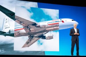 a man standing in front of a large screen with a plane