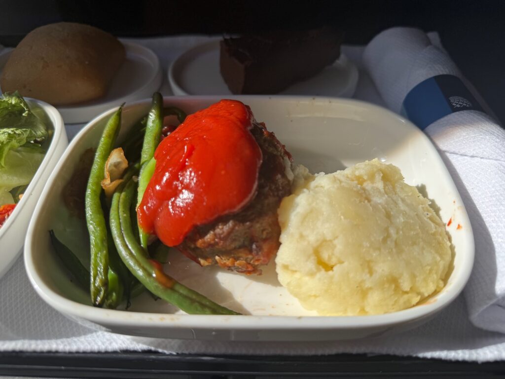 I Rerouted My Trip Just To Eat United Airlines’ Bison Meatloaf And It Was The Best First Class Meal I’ve Had In Years a plate of food on a tray