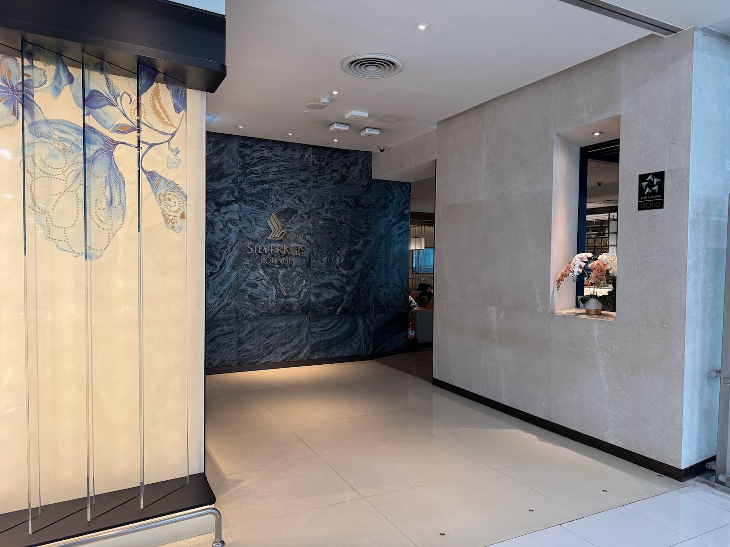 a hallway with a marble wall and a flower vase