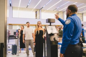 How The Latest Government Shutdown Could Affect TSA Lines, Airports, And Your Travel Plans a man standing next to a woman in a black dress