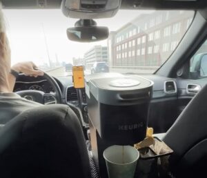 a person driving a car with a coffee machine