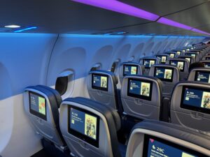 a row of seats with monitors on the side of the plane