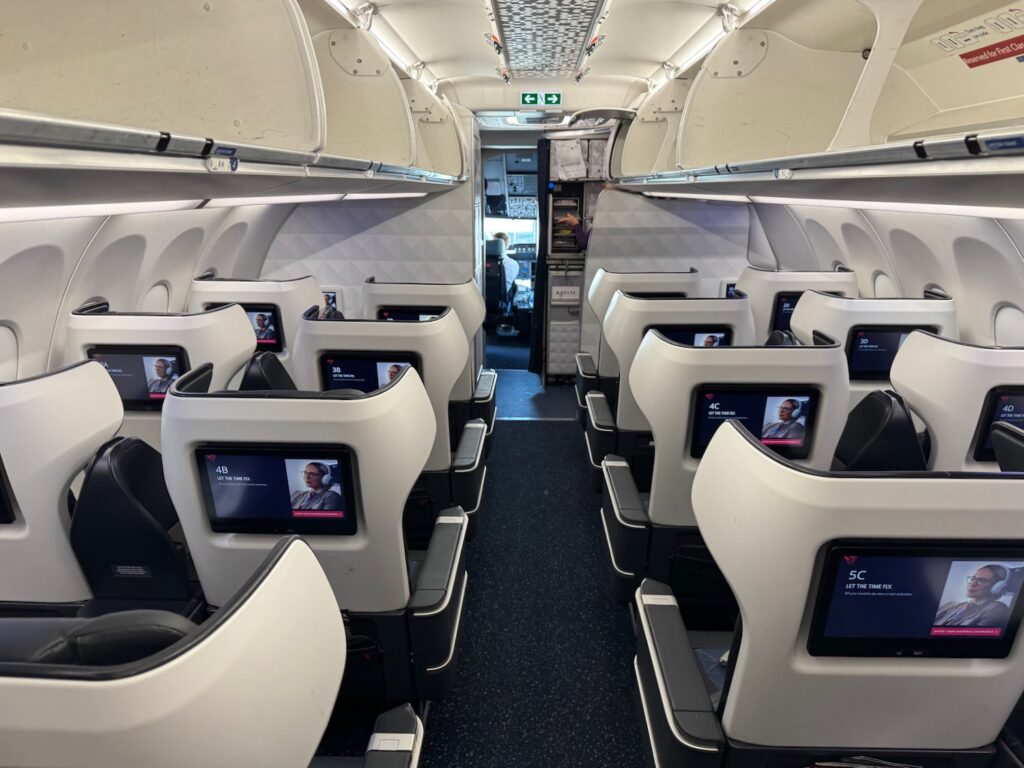 the inside of an airplane with seats and monitors