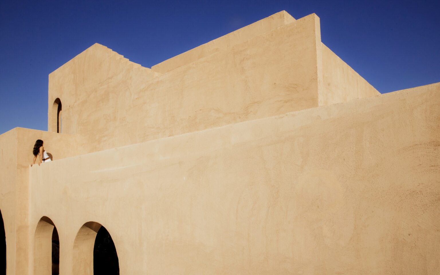 Miniview: Nômade Temple Ibiza – a new cultural sanctuary in Portinatx geometric clay facade against blue sky at _Nomade Temple_